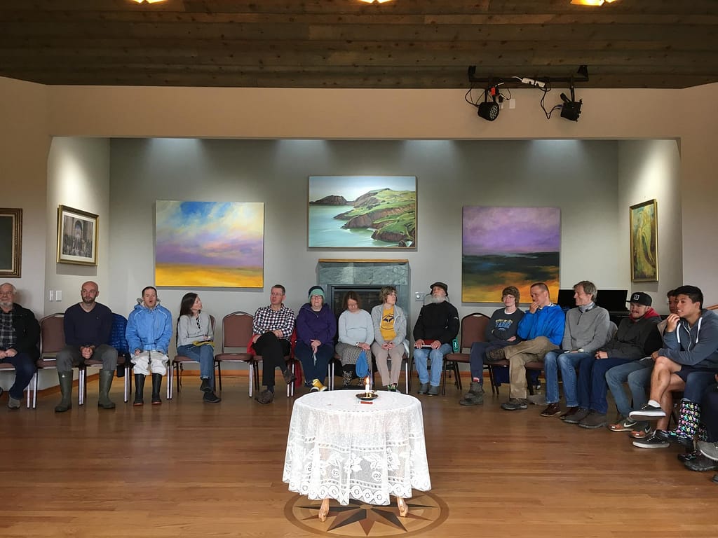 a group of people sit in a circle in a room with beautiful paintings